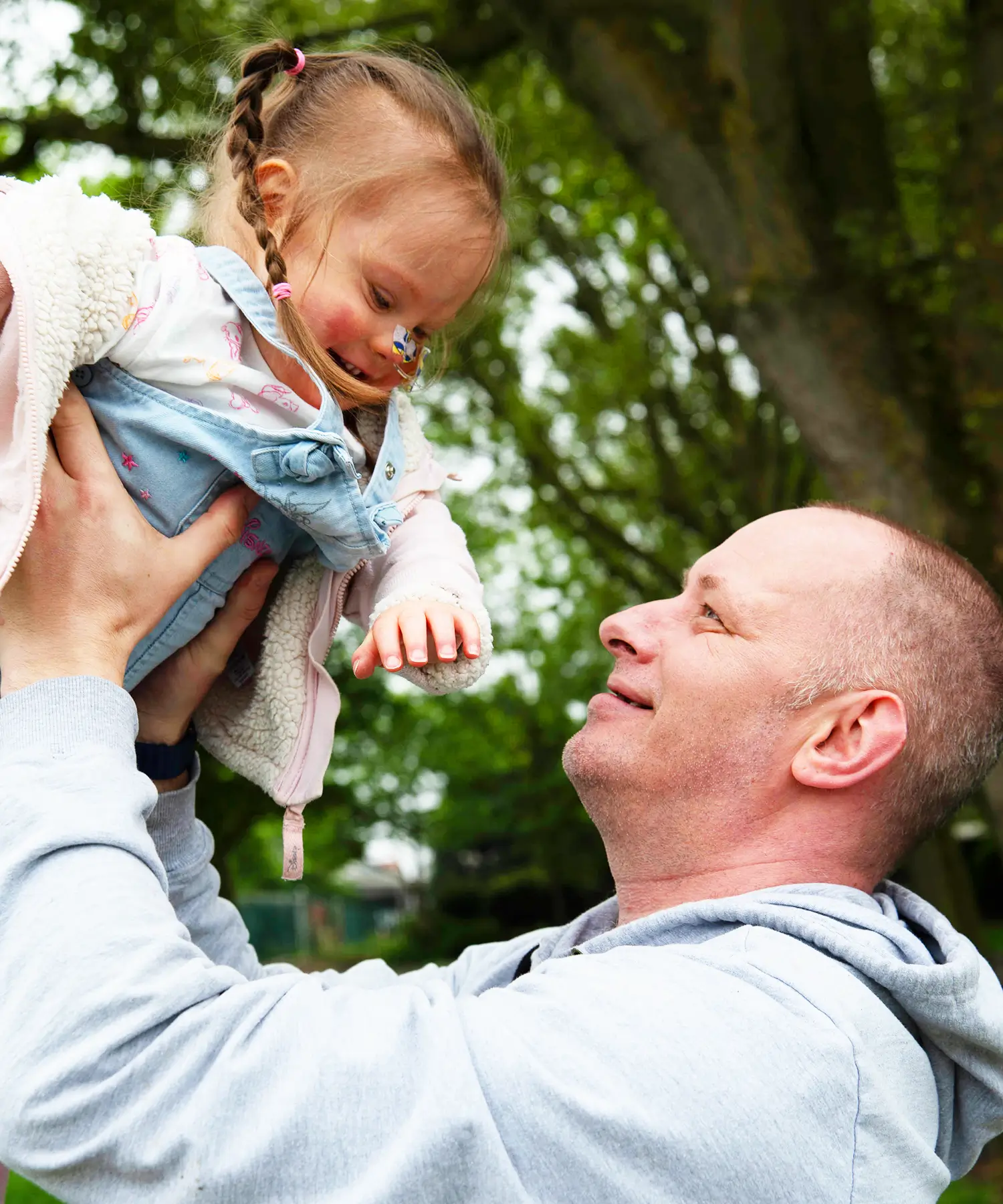 Dad holding a toddler up in her arms.