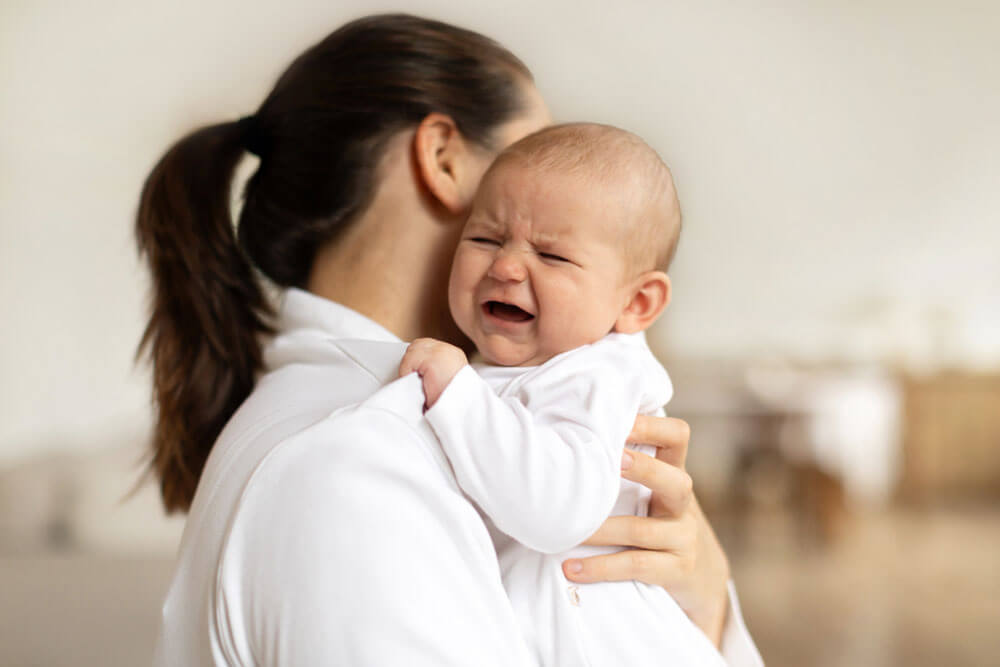 Crying baby on mums shoulder